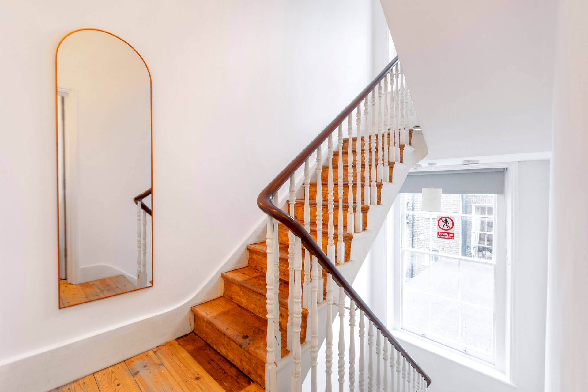 Elegant internal staircase with arched mirror and natural light